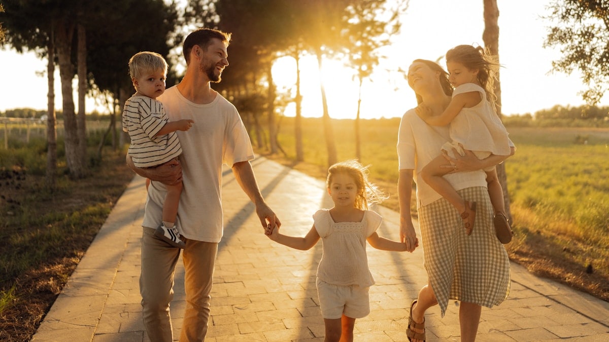 Family walking on path with trees at sunset