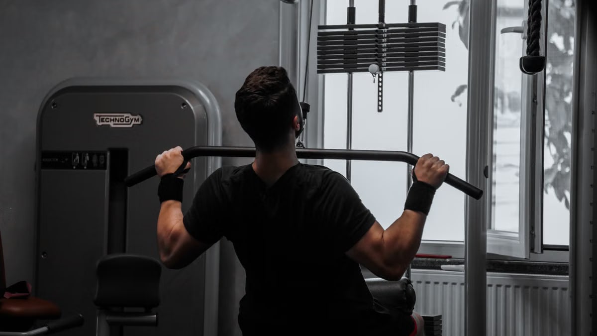 A man working out on a lat pulldown machine in a gym, focusing on strength building.